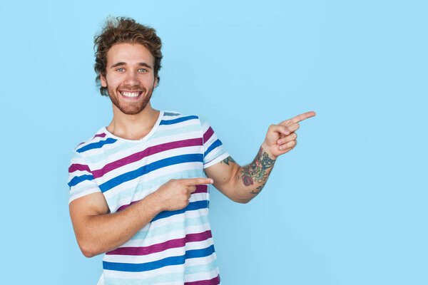Handsome man pointing away on blue