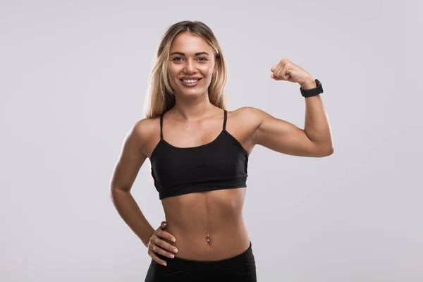 Sonriente mujer en forma mostrando bíceps — Foto de Stock