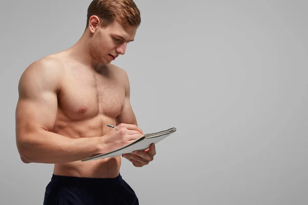 Bodybuilder schrijven in Kladblok — Stockfoto