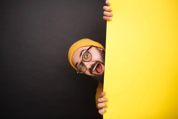 Homme joyeux caché derrière une bannière jaune — Photo