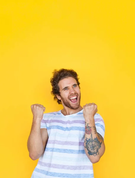 Victorious young man on yellow — Stock Photo, Image