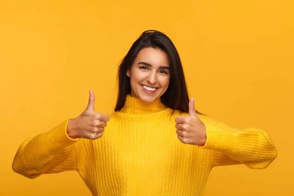 Chica alegre en amarillo sosteniendo los pulgares hacia arriba — Foto de Stock