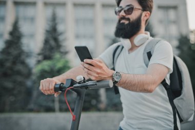Scooter 'da akıllı telefon kullanan sakallı adam.