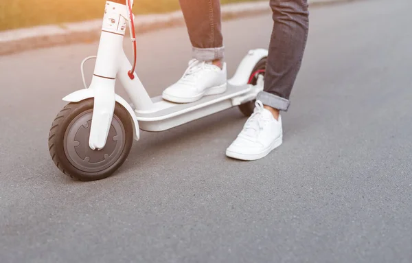 Pessoa em tênis brancos montando scooter elétrico na estrada — Fotografia de Stock