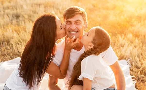Woman and girl kissing father in nature — Stock Photo, Image