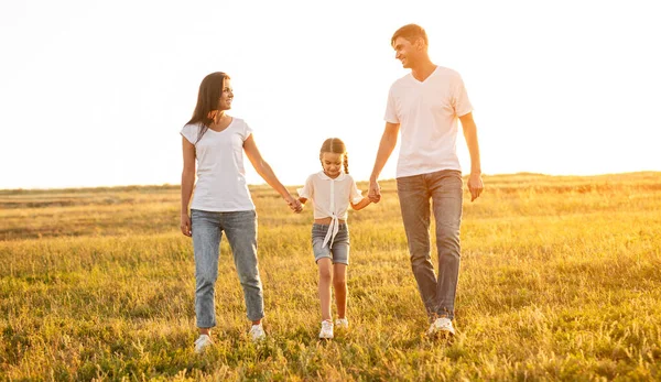 Pais felizes andando com a filha no campo — Fotografia de Stock