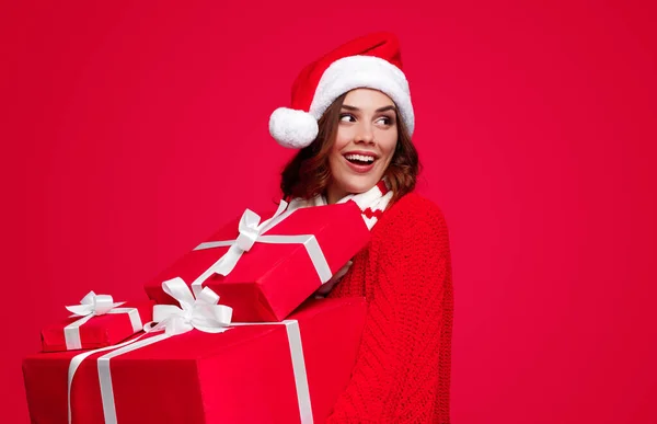 Mujer contenta en Santa sombrero llevando regalos envueltos — Foto de Stock