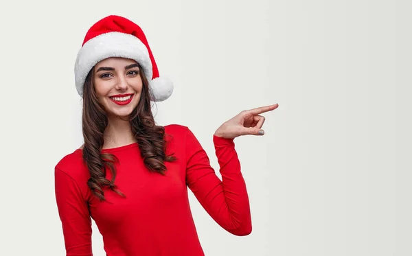 Lady in Santa hoed wijzen opzij en glimlachen — Stockfoto