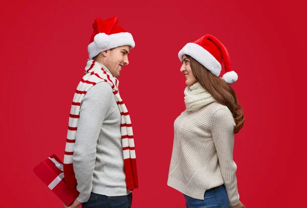 Casal jovem fazendo surpresas durante a festa de Natal — Fotografia de Stock