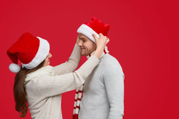 Casal alegre em chapéu de Natal vermelho e camisolas bege — Fotografia de Stock