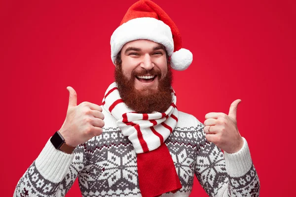 Cara alegre no chapéu de Natal gesticulando polegar ups — Fotografia de Stock