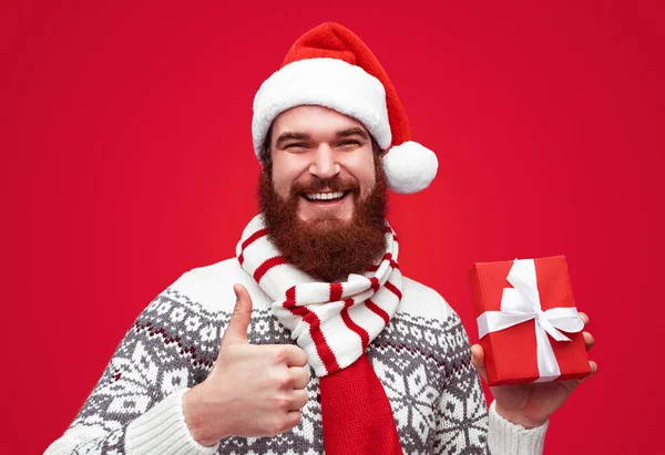 Homem com presente de Natal gesto polegar para cima — Fotografia de Stock