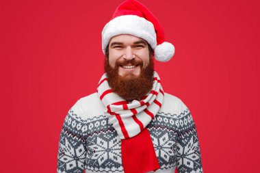 Noel Baba şapkalı ve çizgili eşarplı mutlu bir erkek.