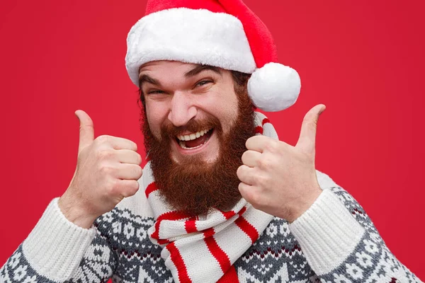 Улыбающийся бородатый парень показывает пальцами вверх — стоковое фото