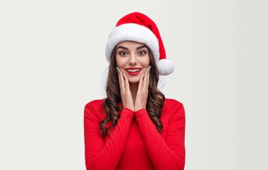 Kameraya gülümseyen Noel Baba şapkalı harika bir kadın.