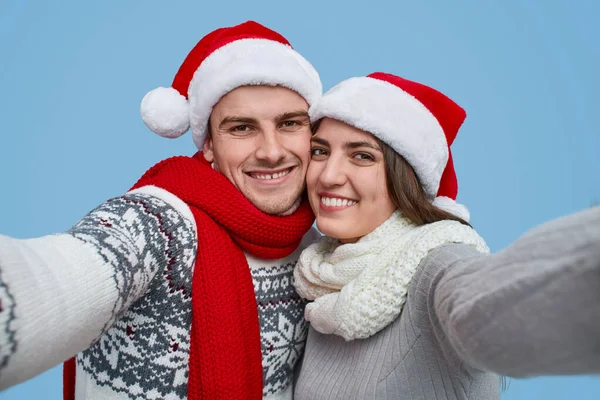 Casal feliz em chapéus de Santa sorrindo e olhando para a câmera — Fotografia de Stock