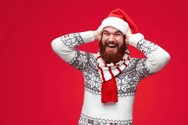Homem alegre em chapéu de Natal cobrindo orelhas — Fotografia de Stock