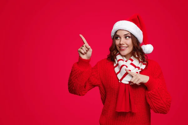 Vrouw met kerstmuts en trui wijst opzij — Stockfoto