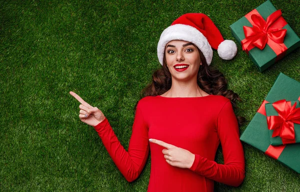 Mujer asombrada señalando a un lado cerca de regalos de Navidad — Foto de Stock