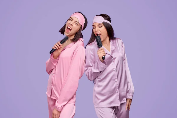 Przyjaciele w piżamie śpiewający do grzebienia — Zdjęcie stockowe
