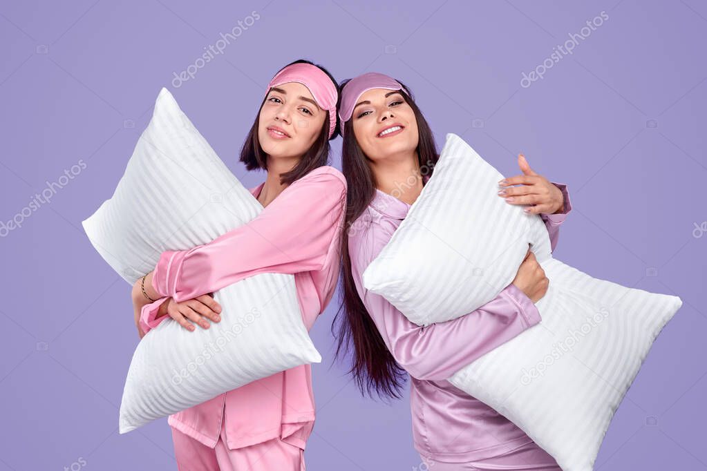 Smiling friends with pillows during pajama party