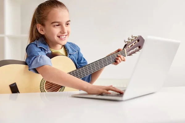 Fille gaie avec guitare en utilisant un ordinateur portable — Photo