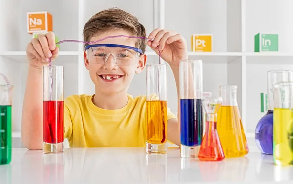 Wesoły chłopiec robi eksperyment chemiczny w laboratorium. — Zdjęcie stockowe