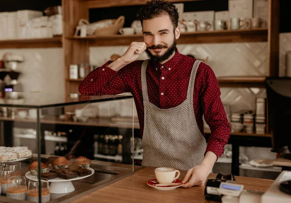 Amistoso camarero sirviendo taza de café en el mostrador en la cafetería hipster — Foto de Stock