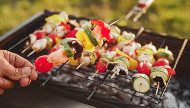 Suratsız aşçı mantar ve sebzeleri şişte pişiriyor.