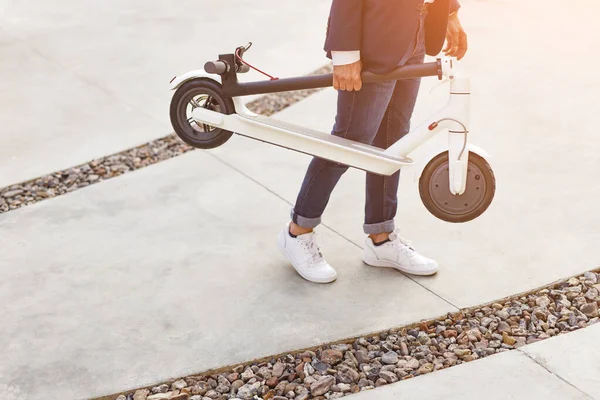 Crop guy carrying modern scooter — ストック写真