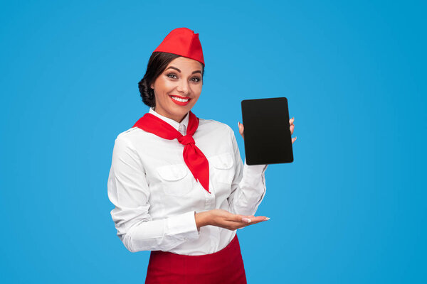 Delighted flight attendant showing tablet with app