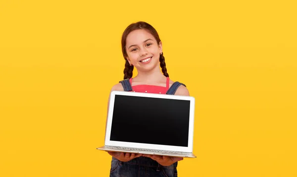 Amistosa colegiala demostrando portátil para la cámara — Foto de Stock