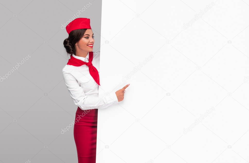 Delighted air hostess pointing at empty placard