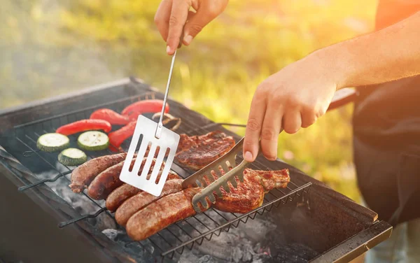 Oříznout kuchaře na grilu při obracení klobás — Stock fotografie