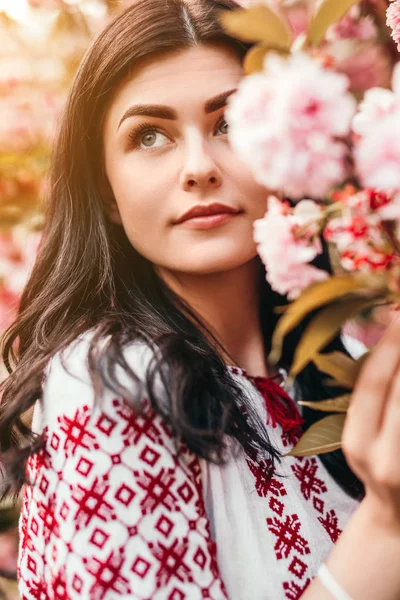 Чуттєва жінка в декоративному вбранні в саду під квітучим деревом — стокове фото