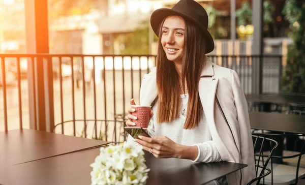 Uśmiechnięta kobieta pijąca kawę i używająca smartfona podczas randki — Zdjęcie stockowe