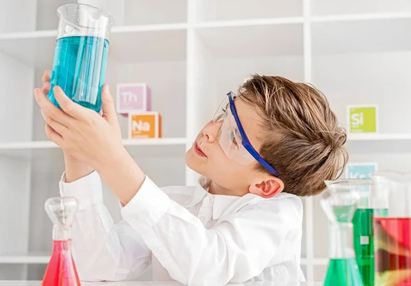 Przemyślany mały chemik badający płyn — Zdjęcie stockowe