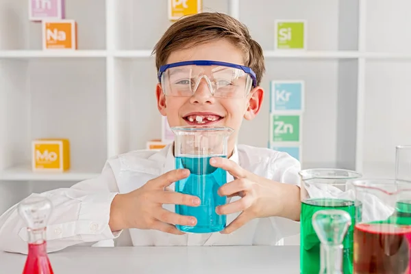 Radosny chemik prezentujący kolbę z niebieską mieszanką — Zdjęcie stockowe