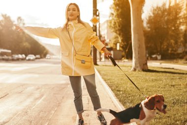 Bir kadın tasmalı bir köpekle yolda araba yakalıyor