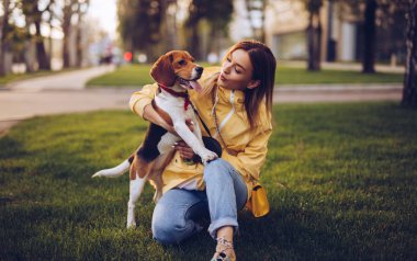 Yeşil çimenlerde sarılmış köpeğe bakan kadına dikkat et.