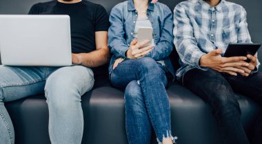 Kanepede modern aletler kullanan iş arkadaşları.