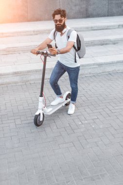 Modern adam elektrikli scooter 'da akıllı telefon kullanıyor.