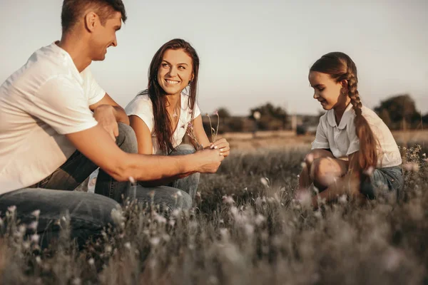 Heureuse famille ramassant des fleurs dans le champ — Photo