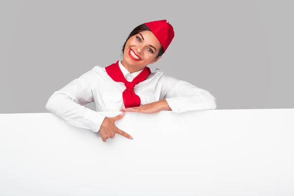 Веселая стюардесса, указывающая на баннер — стоковое фото