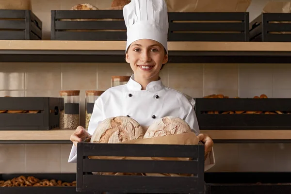 Усміхнений дитина в капелюсі кухаря тримає коробку зі свіжим запеченим хлібом — стокове фото