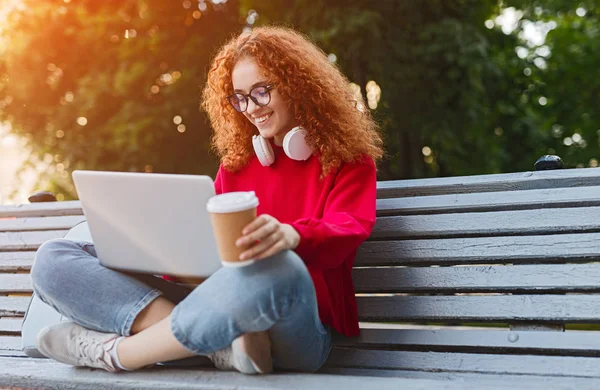 Ginger female student doing homework on bench — Stock Photo, Image