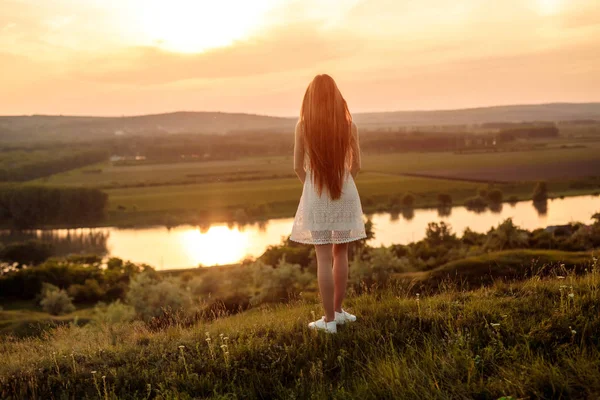 Wanita muda tak dikenal mengagumi matahari terbenam di dekat sungai — Stok Foto