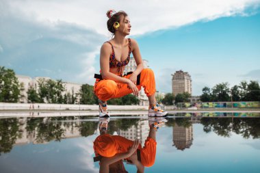 Stadyumdaki su birikintisi yakınlarında müzik dinleyen son moda sporcu kadın.