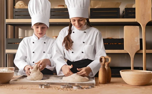 Маленькі пекарі замішують тісто на столі — стокове фото