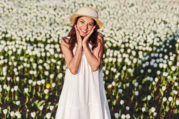 Χαμογελαστή γυναίκα στέκεται στο γήπεδο με άσπρες τουλίπες — Φωτογραφία Αρχείου